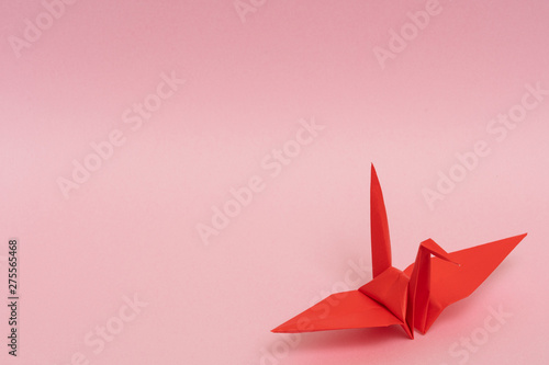 red origami paper crane on pink background