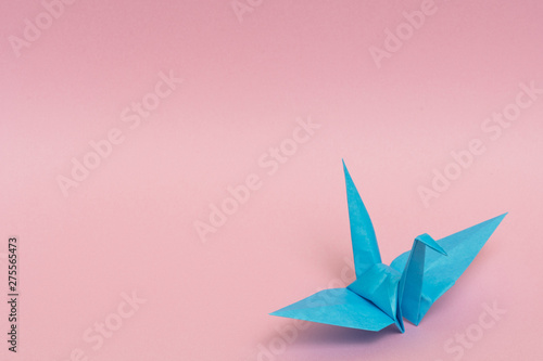 light blue origami crane on pink background