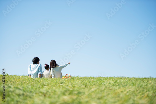 草原でピクニックをするファミリーの後ろ姿