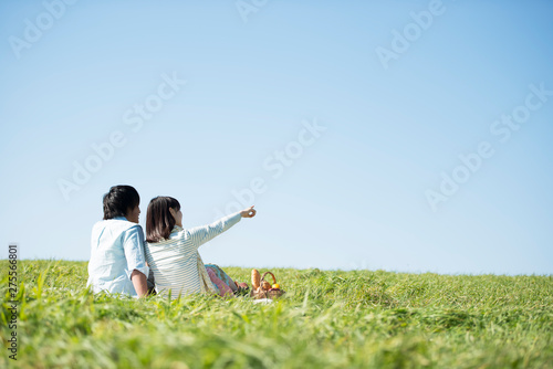 草原でピクニックをするカップルの後ろ姿 photo