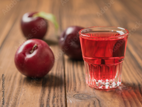 Fotografia A glass of plum liqueur and plum berries on the village table.