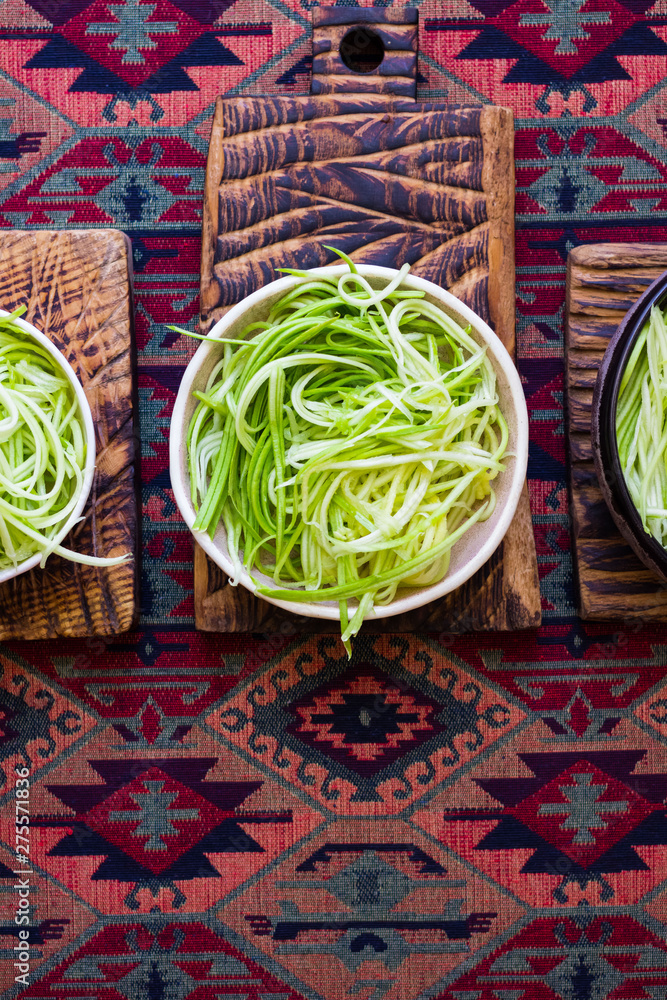 Homemade green zucchini spaghetti or pasta with sauce in bowl with chopsticks. Vegan, vegetarian healthy food. Moroccan colorful background table.