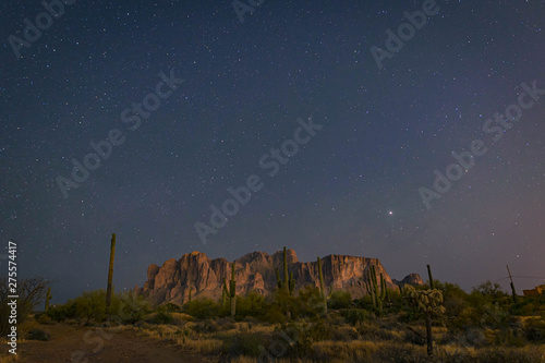 The desert wilderness east of Phoenix  Arizona photographed under clear starry desert skies that seem to glow with color. Desert plants and Saguaro cactus grow around the Superstition mountains 