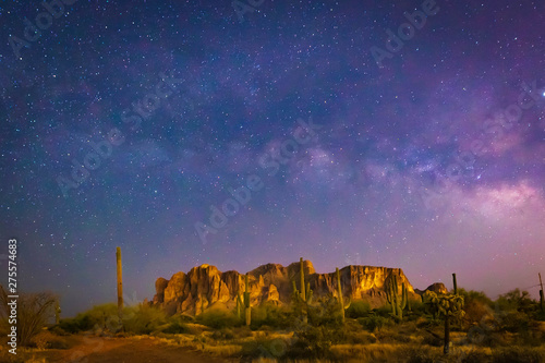 The iconic Superstition Mountains east of Phoenix, Arizona glow under the desert night sky and the epic Milky Way Our world under our universe in star filled dark skies is natural beauty