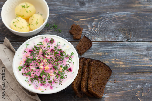 Delicious summer soup, beetroot soup (svekolnik, holodnik) on kefir, with cucumber, boiled eggs and greens. traditional Lithuanian, Russian, Ukrainian, Belorussian or Polish cuisine. on a wooden table photo