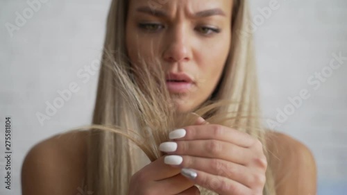 Woman with hair problem. The girl sitting at home, notices that the hair is in bad condition.