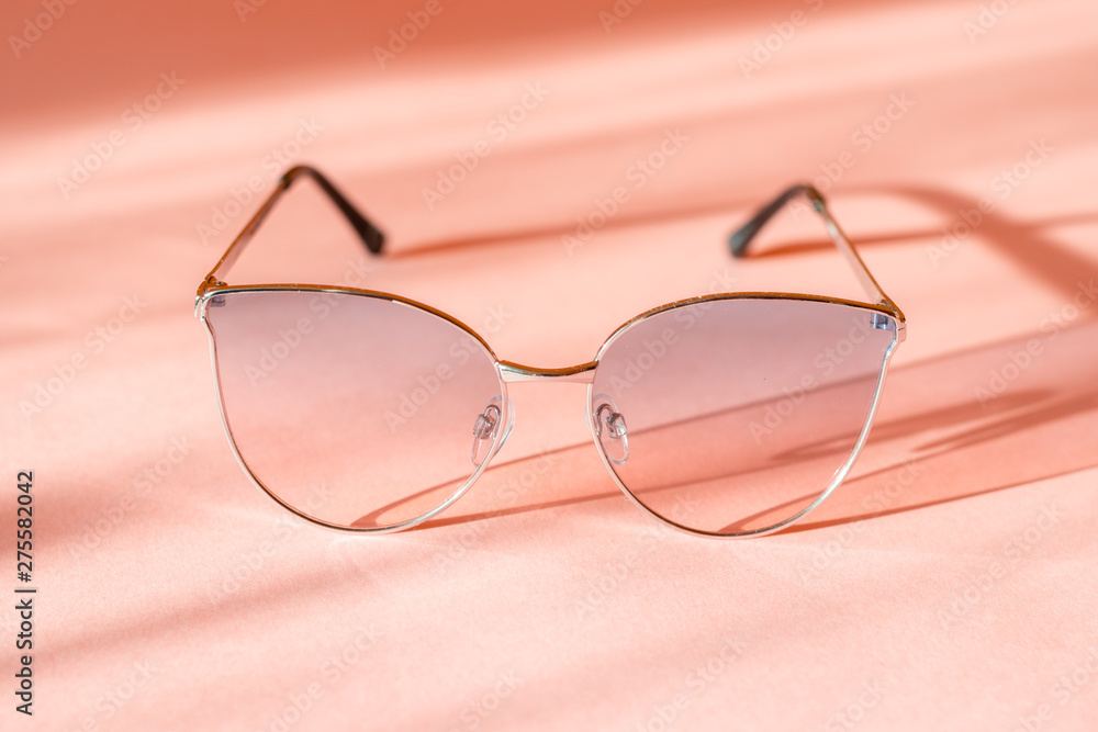 Modern elegant metal frame sunglasses on trendy pink paper background in sunlight. Flat lay. Creative contrast summer image. vacation and party concept. space for text. tropical summer holidays Modern elegant metal frame sunglasses on trendy pink paper background in sunlight. Flat lay. Creative contrast summer image. vacation and party concept. space for text. tropical summer holidays