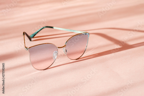 Modern elegant metal frame sunglasses on trendy pink paper background in sunlight. Flat lay. Creative contrast summer image. vacation and party concept. space for text. tropical summer holidays 
