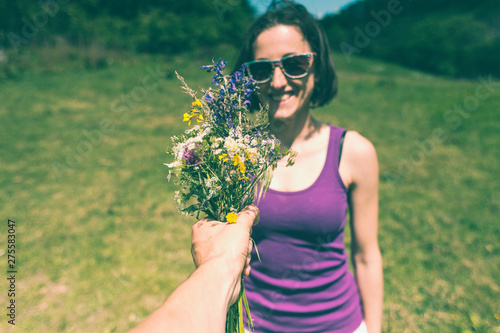 The man holds out a bouquet to the woman.