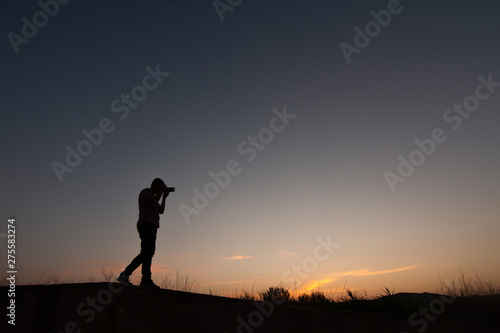 silhouette of man making photos at sunset with reflex camera © robcartorres