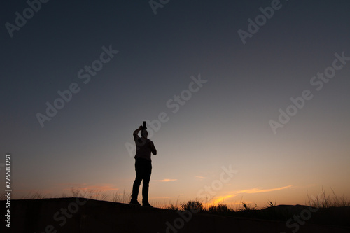 silhouette of man making photos at sunset with reflex camera