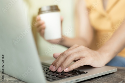 Working woman sitting. She is working with a notebook and is drinking coffee. The concept of women working with technology.