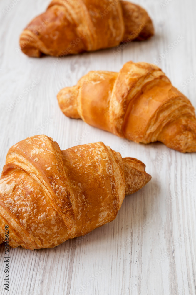 Fresh croissants on a white wooden surface, low angle view. Close-up. Selective focus.