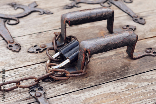 forged handles on wooden doors of a well wrapped with a chain with a padlock