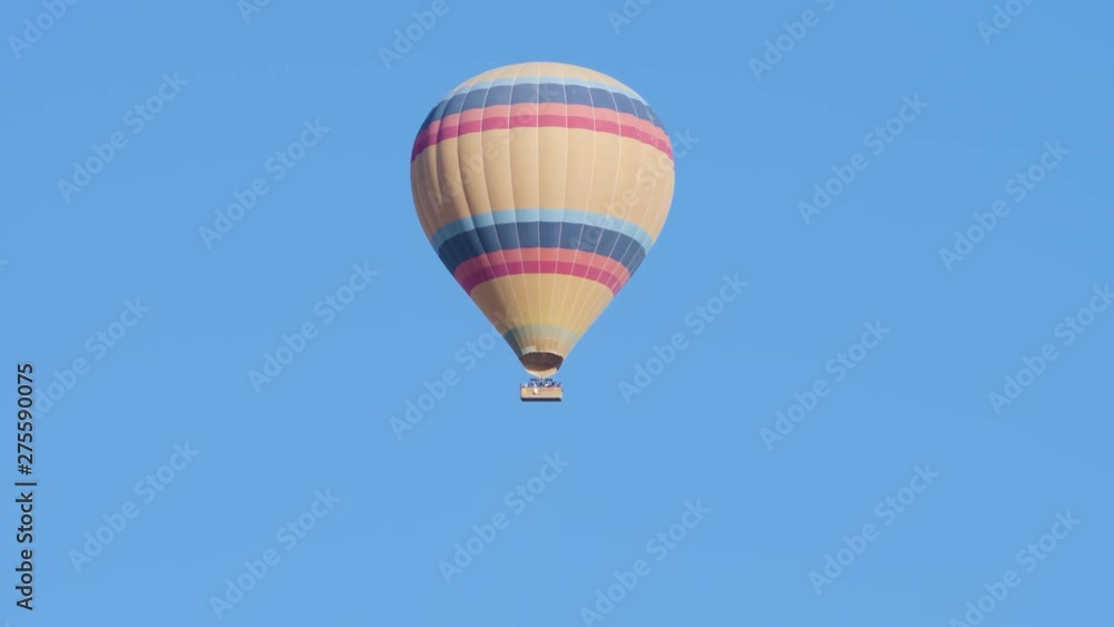 Hot air balloon striped with a basket of tourists flying high in the sky Hot air balloon striped with a basket of tourists flying high in the sky