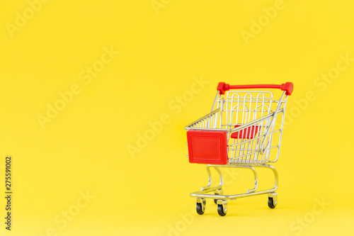 Shopping cart. Close-up of shopping trolley on yellow background. Concept of shopping. Copy space. 