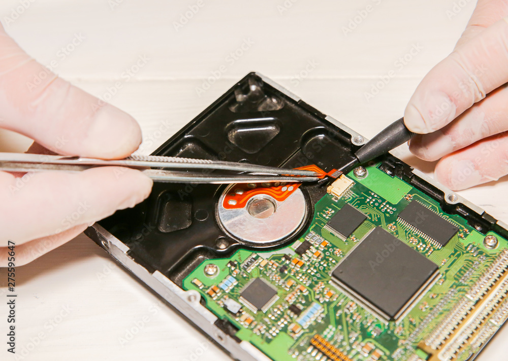 Man repairing hard disk. Inside details of the old personal computer. Broken PC. Screwdriver and pincers in hands. Man repairing hard disk. Inside details of the old personal computer. Broken PC. Screwdriver and pincers in hands.