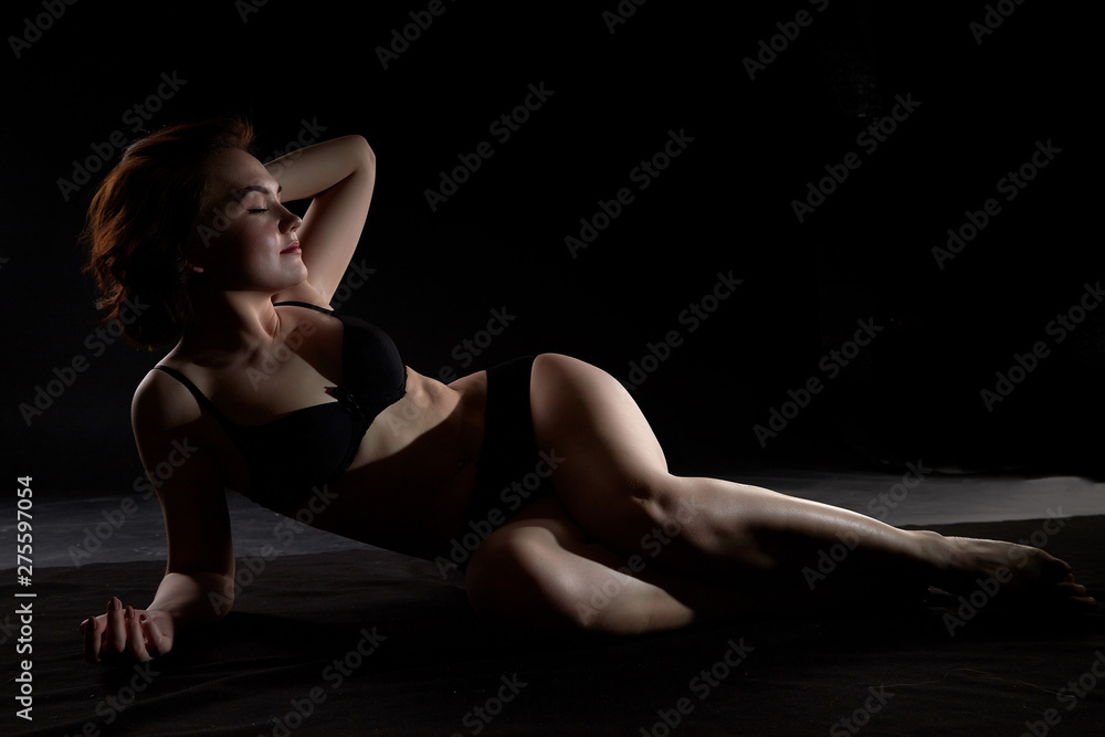 Sexy girl during professional photo shoot in dark room. Model in a black  lingerie and erotic underwear foto de Stock | Adobe Stock