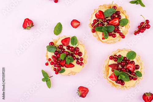 Fototapeta Naklejka Na Ścianę i Meble -  Tarts with strawberries, currant and whipped cream decorated with mint leaves. Top view