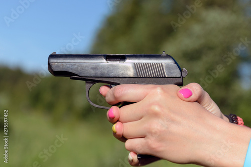 a woman with a beautiful manicure holding, aiming a pistol Makarov. photo