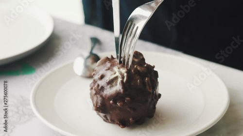Young woman cutting breaking and eating dessert a la Ferrero Rocher in cafe at lunch