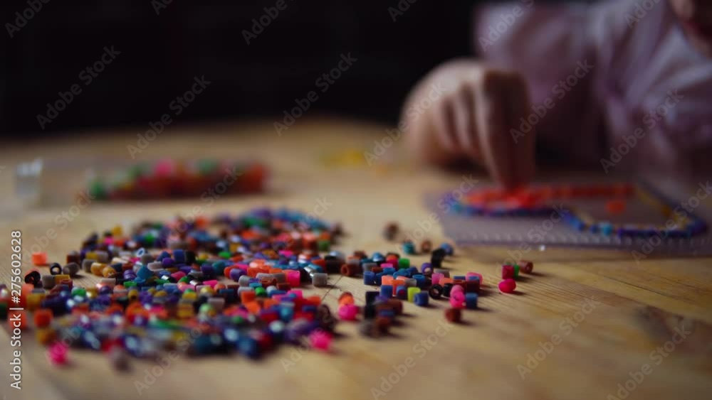 Little cute girl makes a colorful heart from mosaic. The child prepares a gift for the day of the mother, father or valentine. Little cute girl makes a colorful heart from mosaic. The child prepares a gift for the day of the mother, father or valentine.