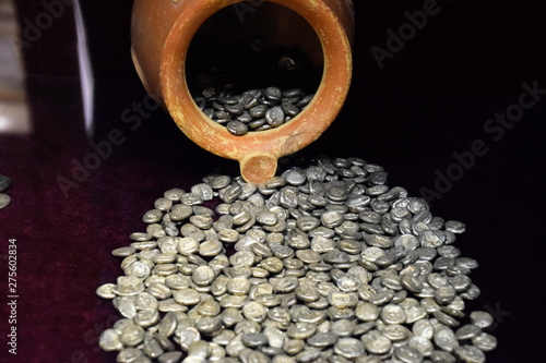Silver coins poured out of clay pot photo