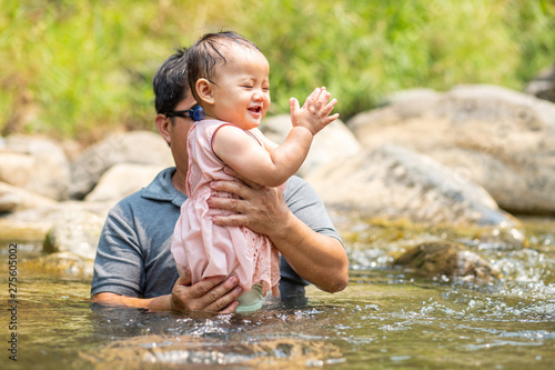 Fototapeta Naklejka Na Ścianę i Meble -  Asian man wearing goggles carrying his baby girl in water