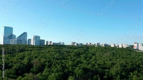 Green city in Russia.Camera flies over the forest and approach buildings in the dormitory area. Part 1