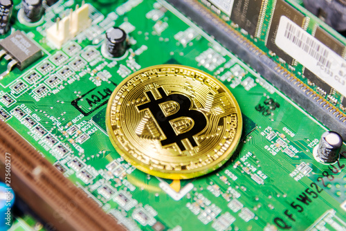 Close up of golden bitcoin on green printed circuit board 