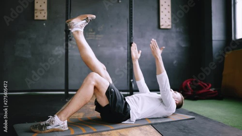 Man in good fit does abs exercises or curl up for improving sports training, single-leg toe touches, best exercises for office workers. Intermediate no equipment exersize to endurance for abs and core