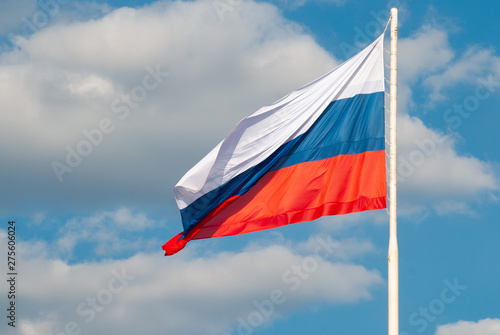 Russian flag waving in the wind against the blue sky,