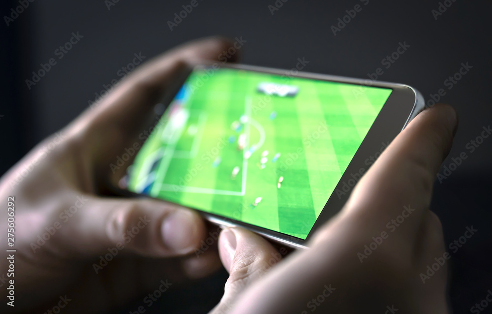 Watching football and sport stream with mobile phone. Man streaming soccer  game live, video replay or highlights online with smart device. Sports fan  and program of tv network in smartphone screen. Stock
