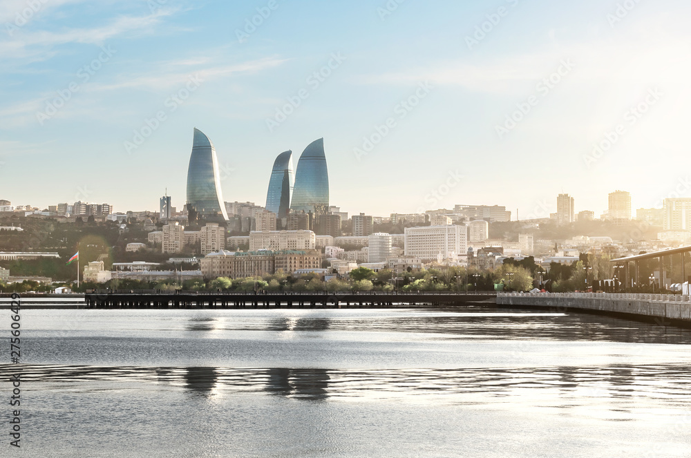 Baku city at sunset. Panoramic view of the skyline with sea boulevard, pier and Flame towers in the background. The capital city of Azerbaijan in summer.