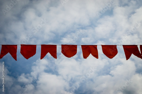 Le bandierine rosse di una festa di paese si stagliano nel cielo azzurro pieno di nuvole photo