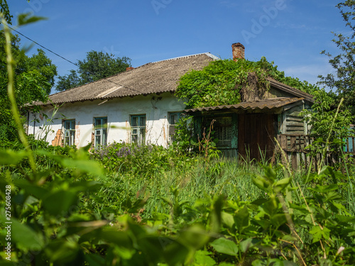 Old, ruined house overgrown with thick grass. Empty house, which have left people