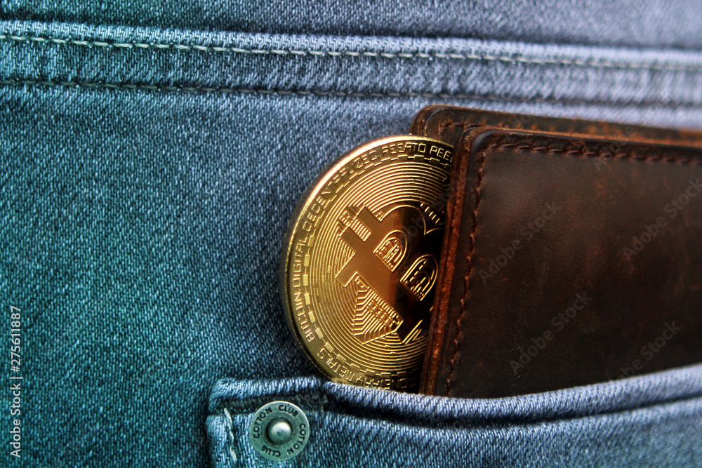 dark brown men's wallet made of high-quality genuine leather, from which you can see electronic money; golden Bitcoin is in the back pocket of men's gray jeans dark brown men's wallet made of high-quality genuine leather, from which you can see electronic money; golden Bitcoin is in the back pocket of men's gray jeans