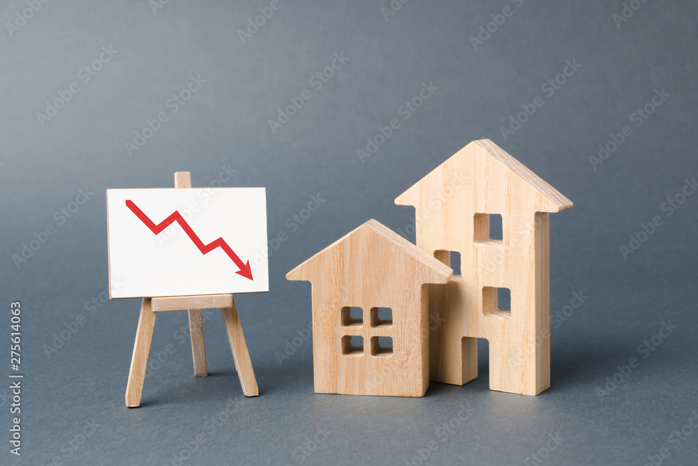 Two wooden houses and a poster with a symbol of falling value. concept
