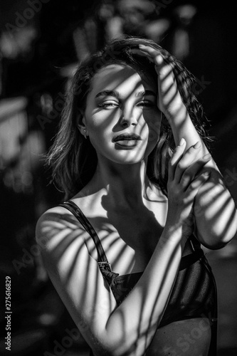 Black and white portrait of a beautiful young girl with a shadow pattern on the face and body in the form of stripes. Fashion concept © Detkov D