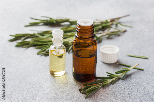 Rosemary essential oil in a glass bottle with fresh branch rosemary herb on grey table for spa,aromatherapy and bodycare.Copy space.