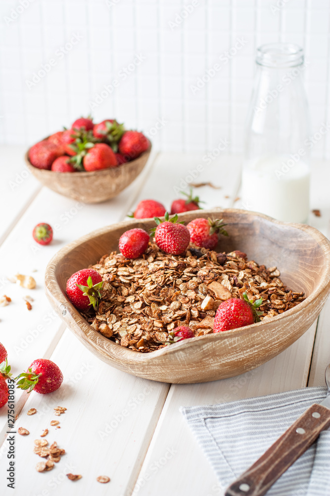 Homemade granola with strawberry and milk in wooden bowl Homemade granola with strawberry and milk in wooden bowl