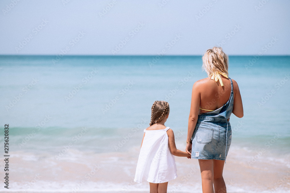 Rear view of a mother and daughter standing on the beach and looking on the sea. Family vacation. Phuket.