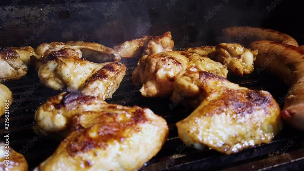 Smoke rising from hot barbecue full of juicy chicken wings and sausages. Grilling on charcoal bbq while having a picnic with family at home. Smoke rising from hot barbecue full of juicy chicken wings and sausages. Grilling on charcoal bbq while having a picnic with family at home.