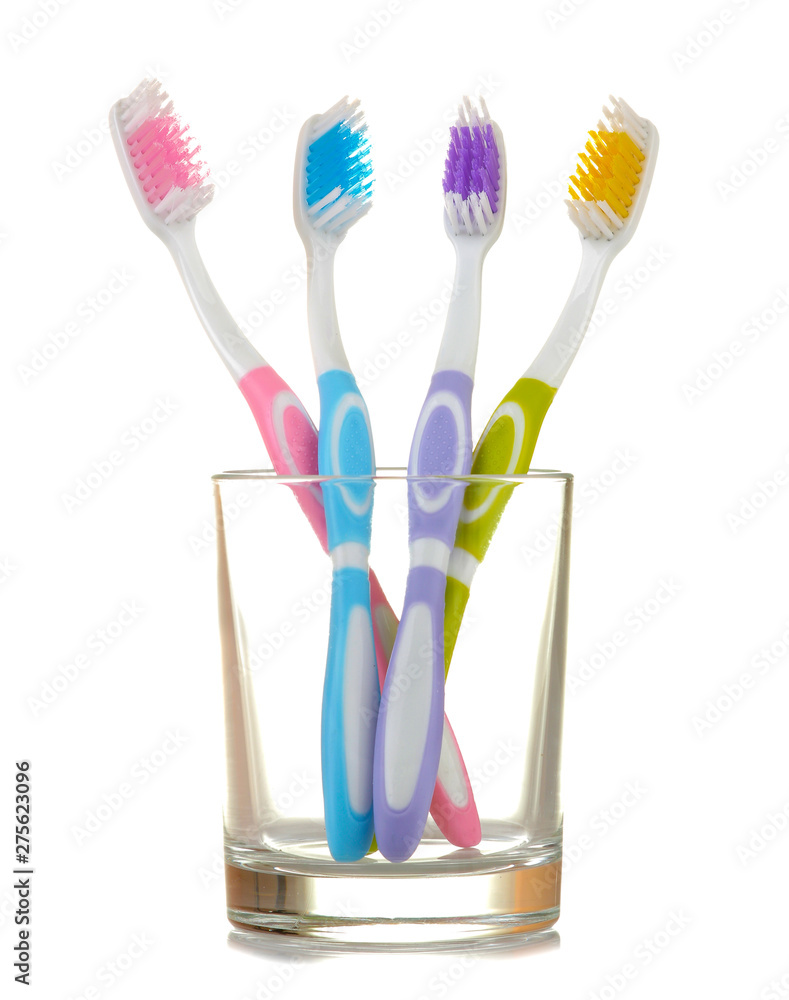 Multi-colored toothbrushes in a glass beaker on a white isolated background. Oral hygiene. Multi-colored toothbrushes in a glass beaker on a white isolated background. Oral hygiene.