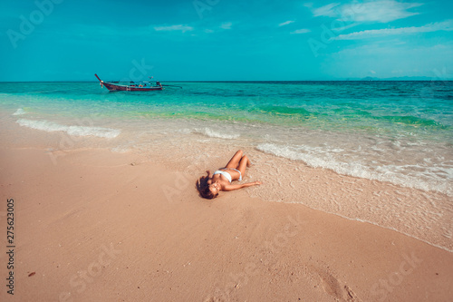 Fototapeta Naklejka Na Ścianę i Meble -  Young and pretty girl model in a bikini sunbathing on the beach resort of the Andaman sea. Boat and blue sea background.