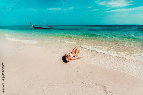 Fototapeta Naklejka Na Ścianę i Meble -  Young and pretty girl model in a bikini sunbathing on the beach resort of the Andaman sea. Boat and blue sea background