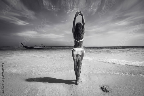 Black-white photo of a Sexy back of a beautiful unrecognizable luxury slim woman with perfect tan and curly hair relaxing on the summer vacation. Phuket. Thailand. Beautiful sea and boat  background