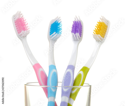 Multi-colored toothbrushes in a glass beaker on a white isolated background. Oral hygiene.