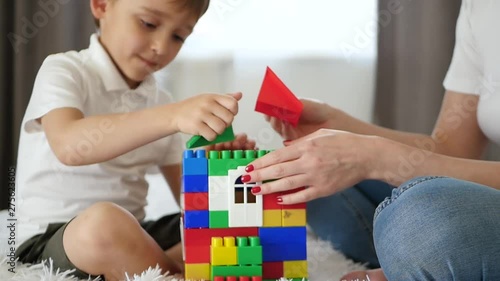 Close-up of the house from meccano. A happy family builds a house of colored blocks. photo