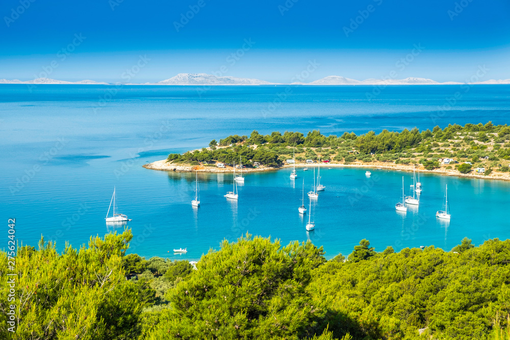 Panoramic view on Kosirina beach bay on Murter island in Croatia, anchored sailing boats and yachts on blue sea